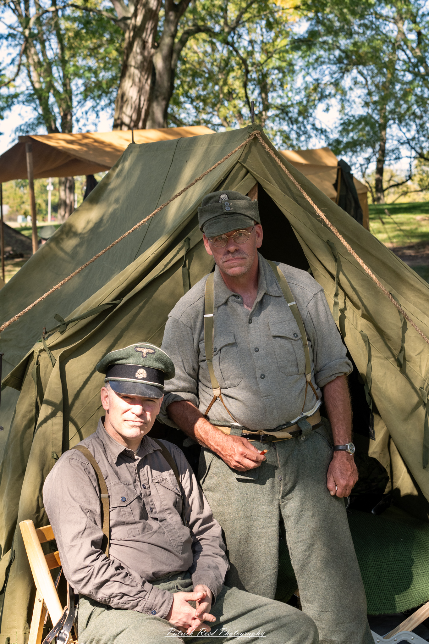 "Group portrait of German soldiers at Lauer Farms, showcasing their distinctive World War II uniforms and equipment. The soldiers stand together with serious expressions, embodying the complexities of war. The rustic backdrop of the farm contrasts with the military presence, highlighting the juxtaposition of daily life and the realities of conflict. Details such as insignia and gear reflect their military identity. Soft natural light enhances the scene, creating a dramatic yet respectful atmosphere."